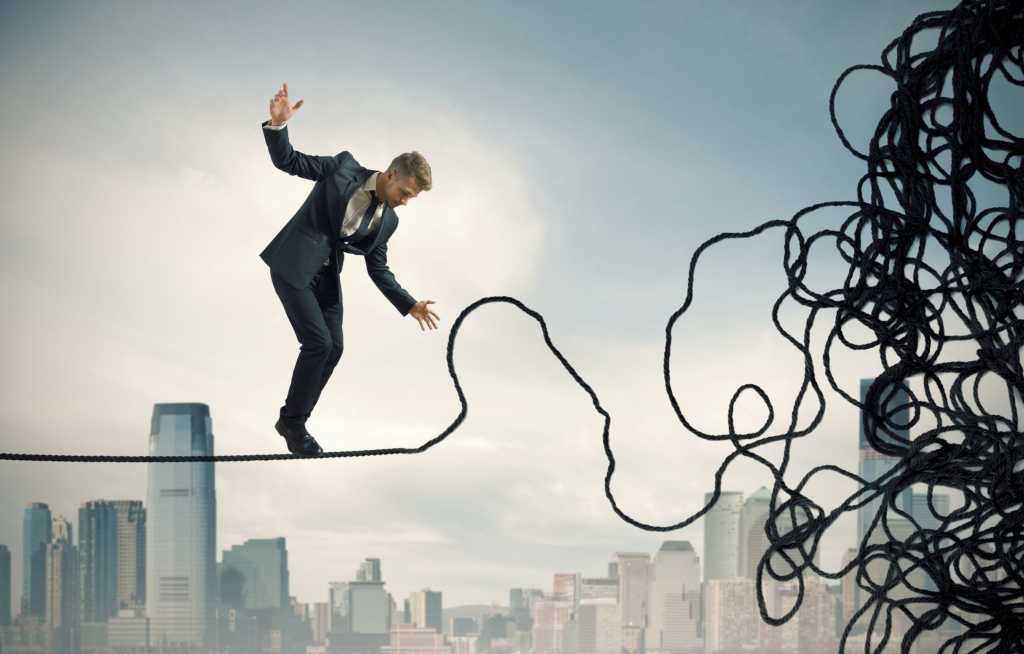 Man walking on tight rope which is unraveling problem mess danger risk