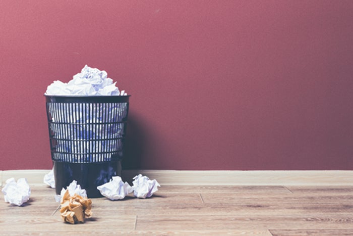 overflowing trash can with balled up paper