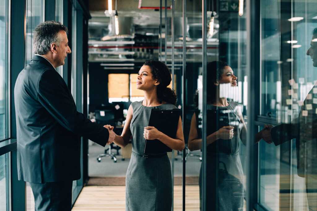 A man and woman shake hands. / handshake / teamwork / collaboration / partnership / trust / greeting