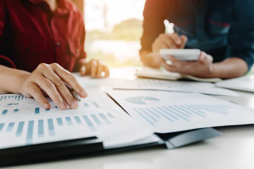 One person uses a calculator while another reviews financial data.