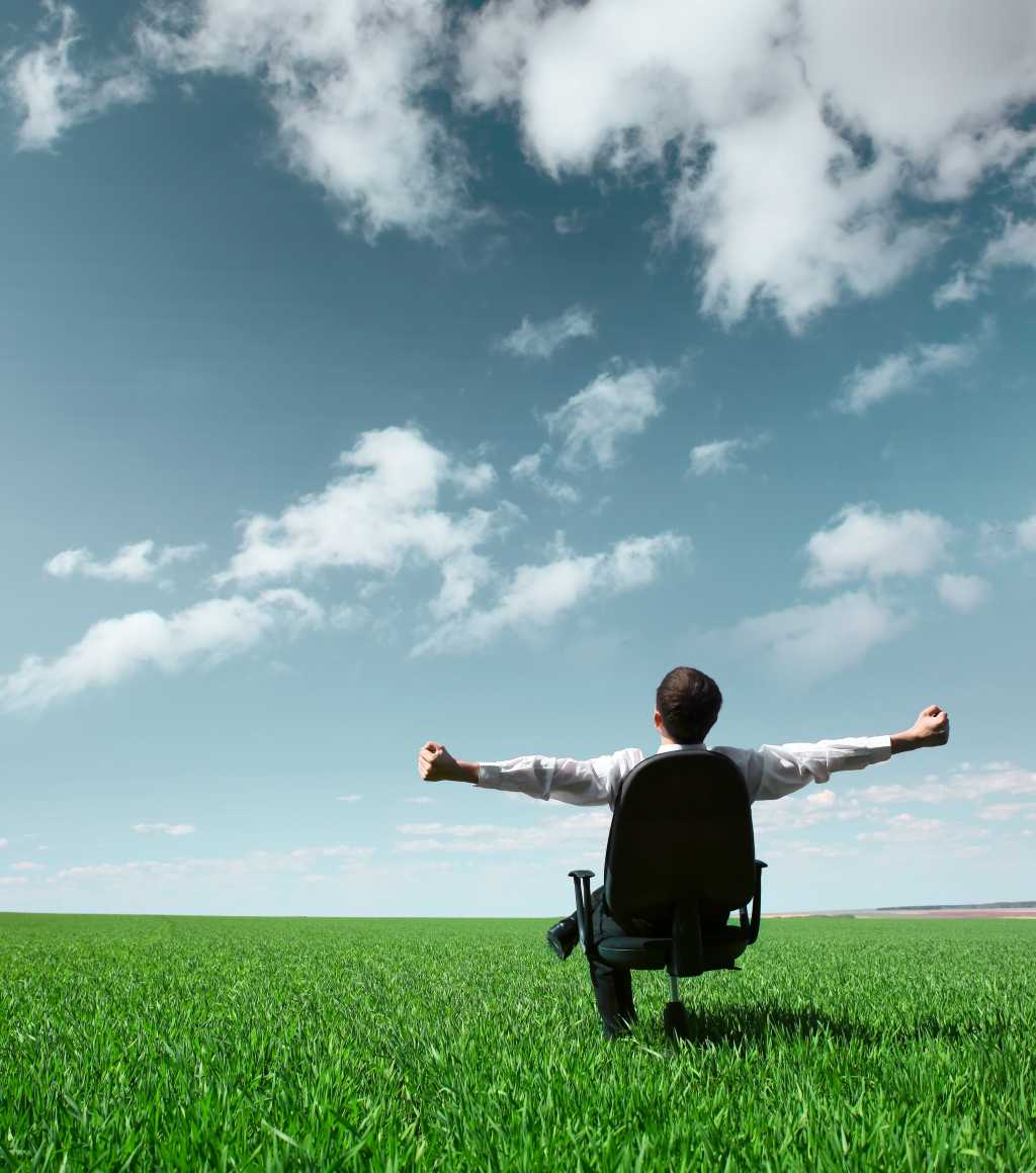 Man relaxing in chair on open grassy field with blue sky