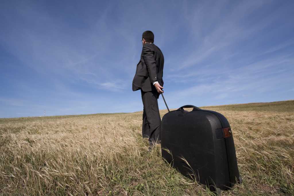 Executive dragging suitcase unemployed or fired