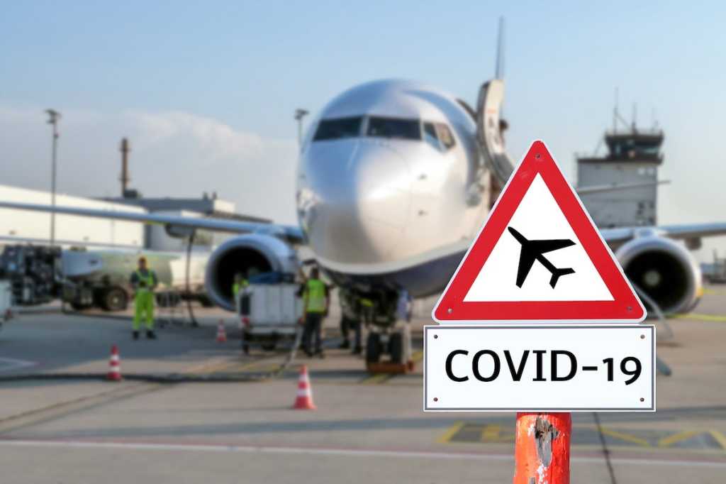 Airplane at the airport with a coronavirus sign in the foreground [Covid-19, travel, planes]