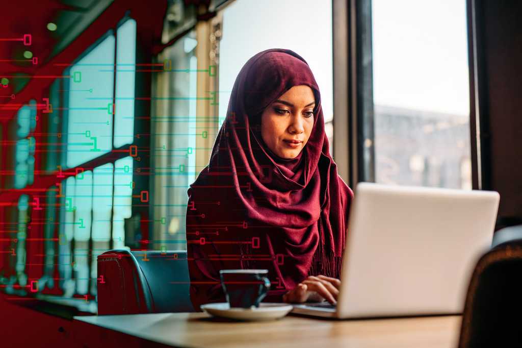 CIO | Middle East > A woman uses a laptop amidst abstract binary data.