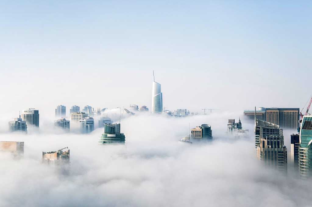 city skyscrapers emerge from foggy cloudy / environment pollution / uncertainty / unknown future