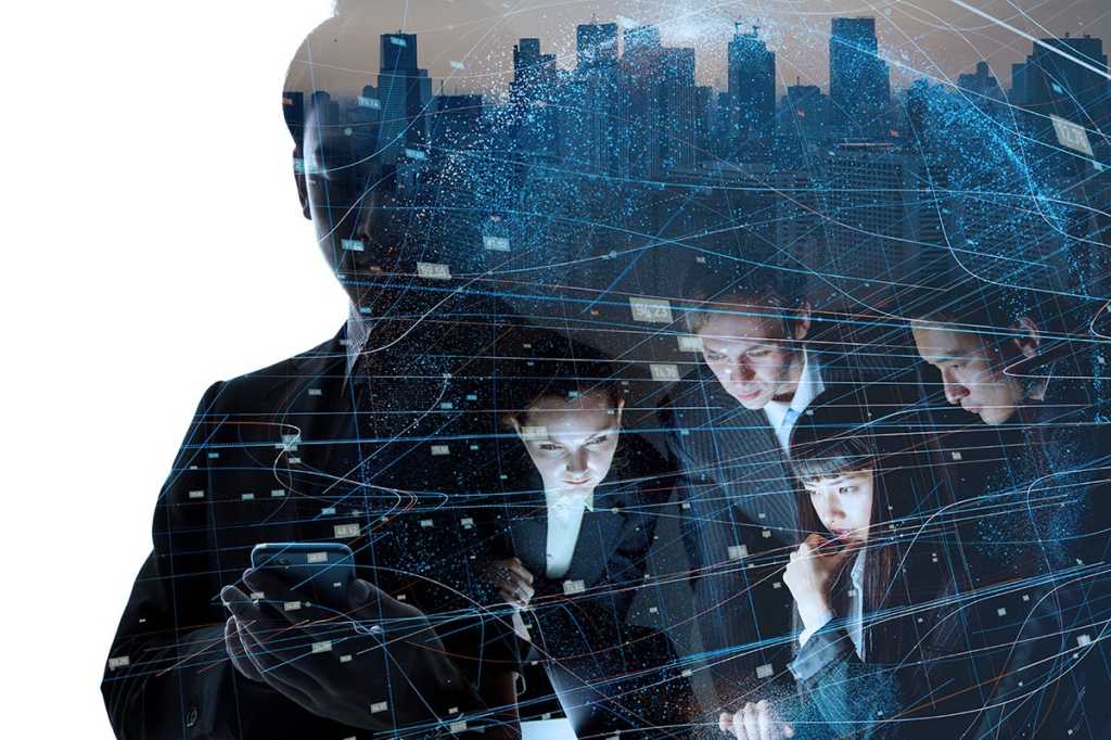 multiple-exposure image - a businessman, a team at a laptop, and data connections against a skyline