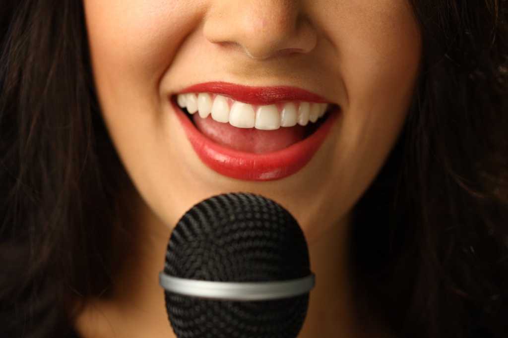 A woman speaking into a microphone. [close-up]
