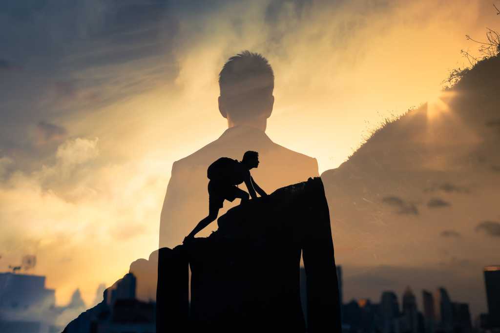 A businessman's silhouette and city skyline merged with a shot of him climbing a mountain.