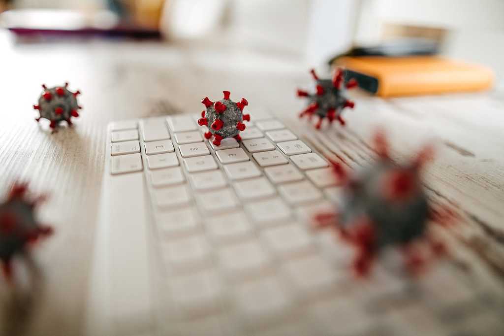 COVID-19 coronavirus cell models lie scattered across a keyboard and workspace.