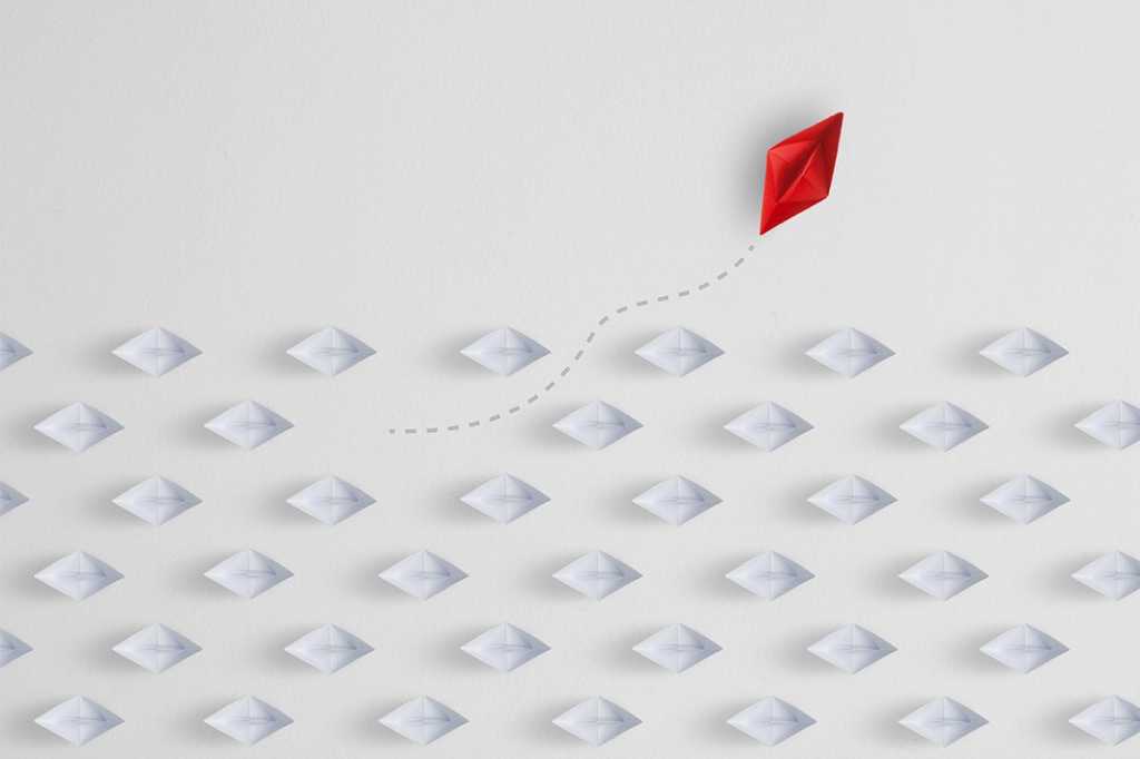 one red paper boat breaking from a formation of white boats