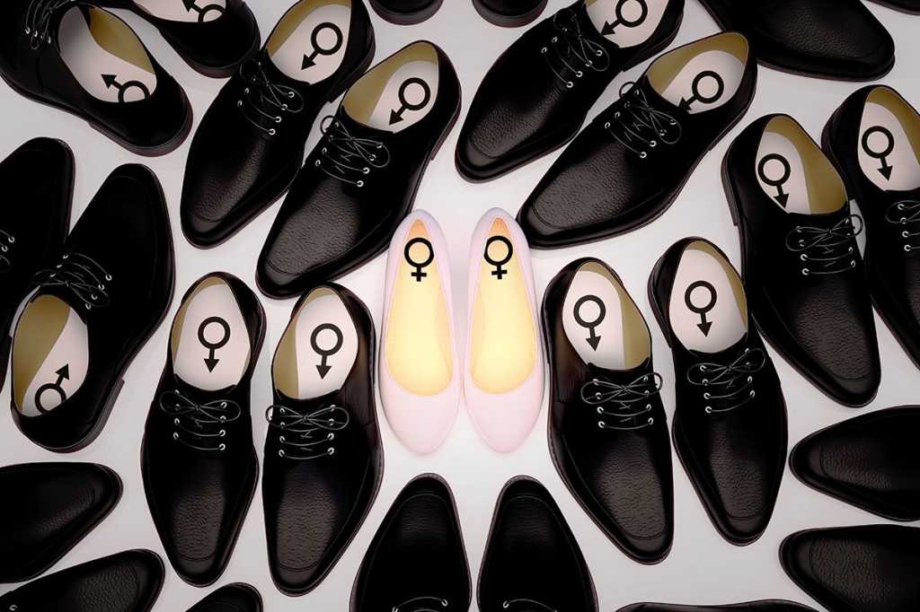 a single pair of white women's shoes surrounded by pairs of black men's shoes