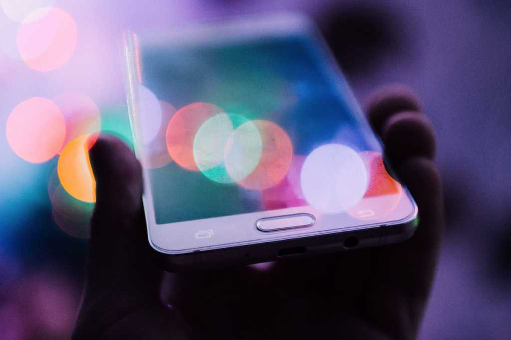 hand holding smart phone with colorful reflection wireless mobile apps by rodion kutsaev via unspla