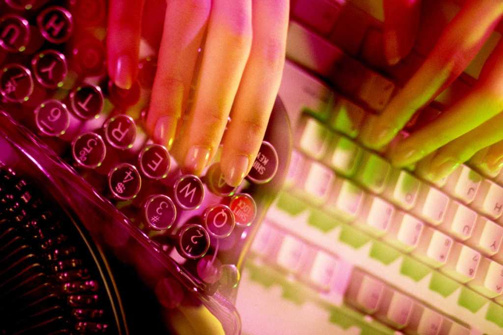 hands use both an antique typewriter and a more modern computer keyboard