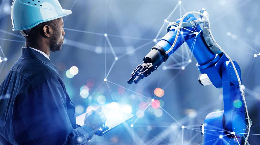 Man in hard hat looking at robotics arm