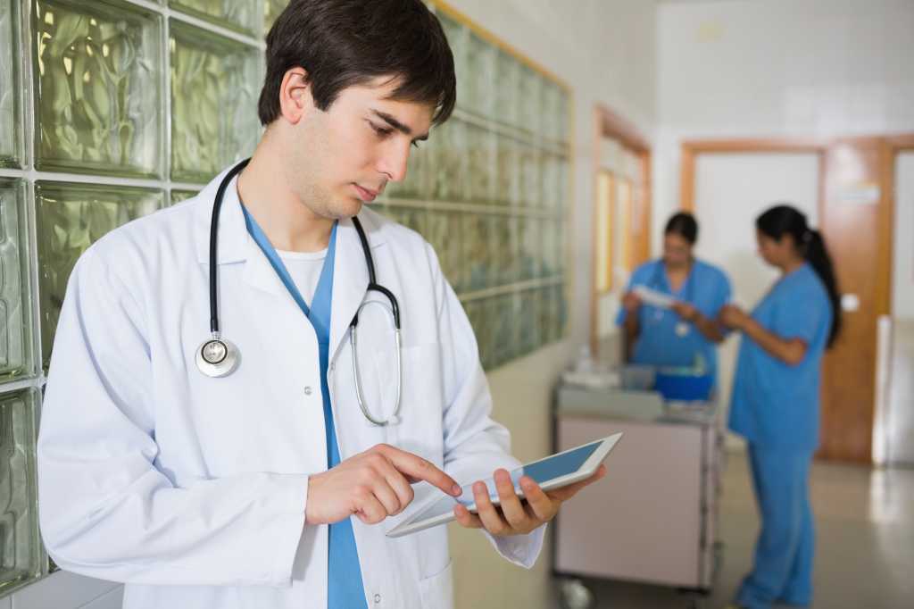 male doctor holding a tactile tablet in a hallway 151908036