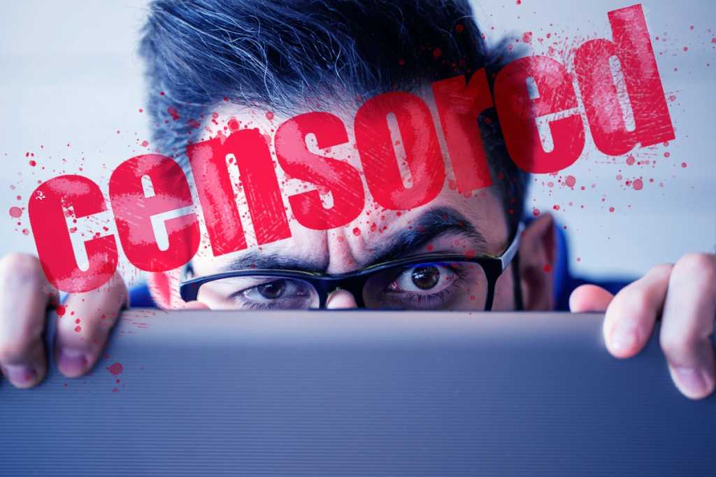 man hiding behind laptop computer sneaky employee hiding censorship by xesai getty images