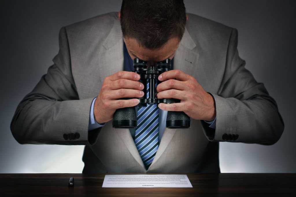 man with binoculars reading the fine print contract examine