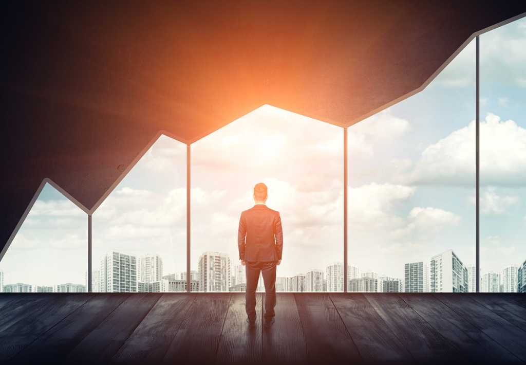businessman looks at a skyline through a window shaped like a progressively increasing line graph