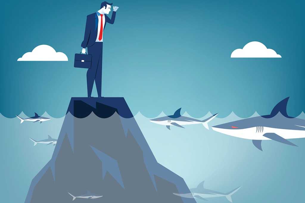 businessman stranded on an outcropping of rock in the ocean, surrounded by sharks