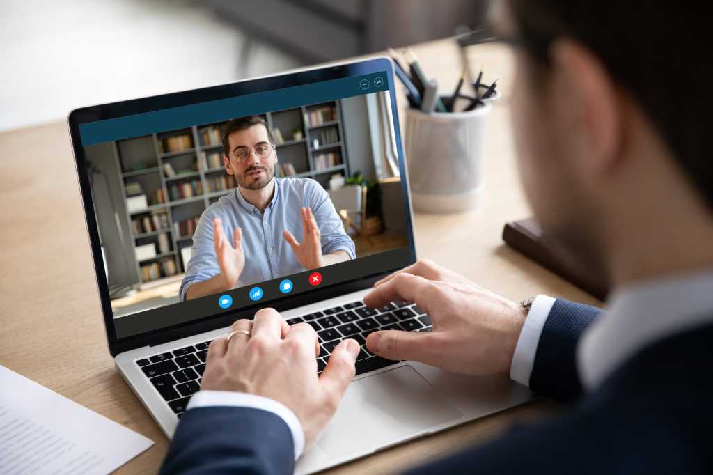 Back view of businessman talk with male business partner using video call on laptop discuss work project online, male client talk with colleague or coworker, speak on webcam conference on computer