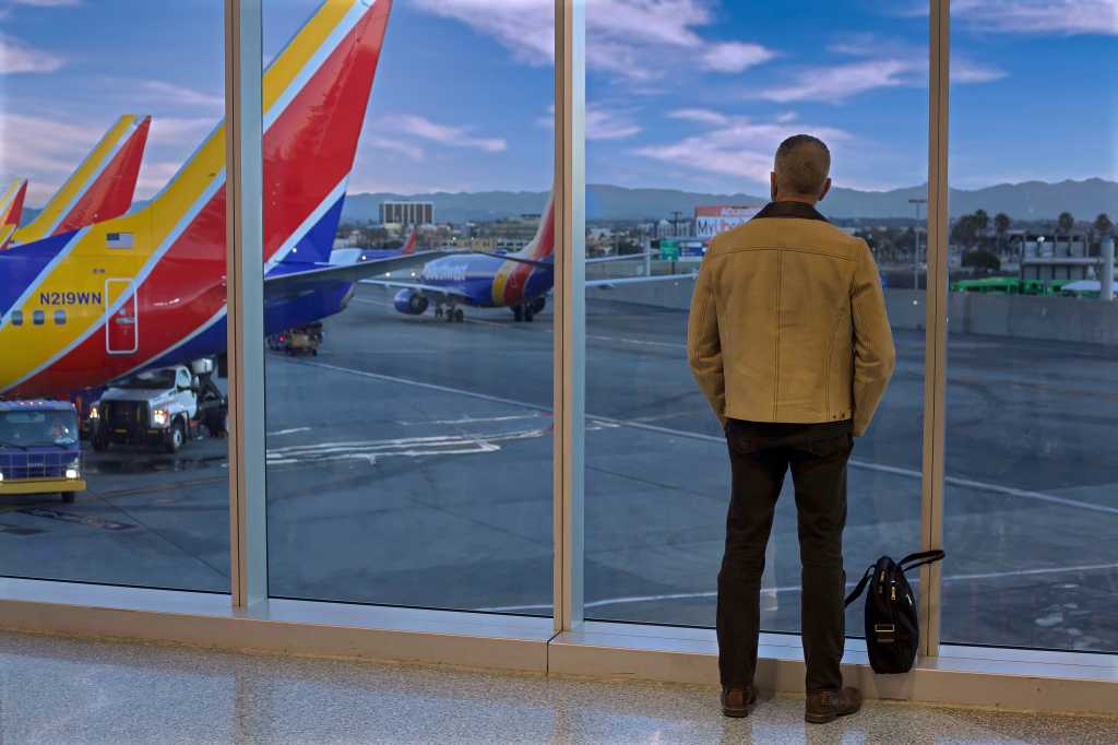 Los Angeles - December 17, 2019: Selective focus on Man watching planes from Southwest Airlines departure gate window