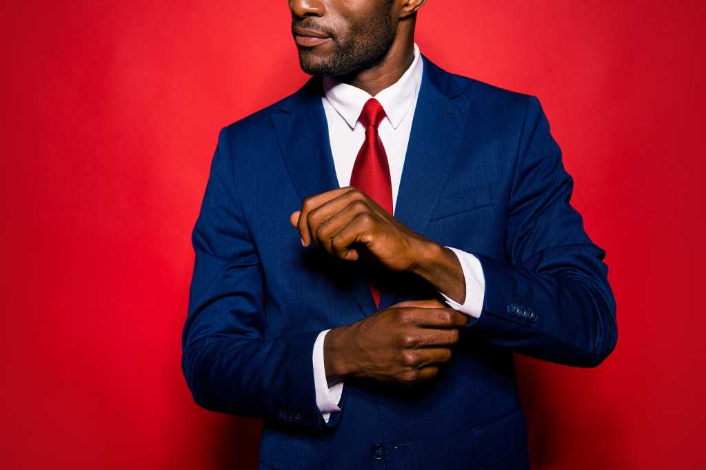A businessman in a suit adjusts his cuffs. / leadership / readiness / success