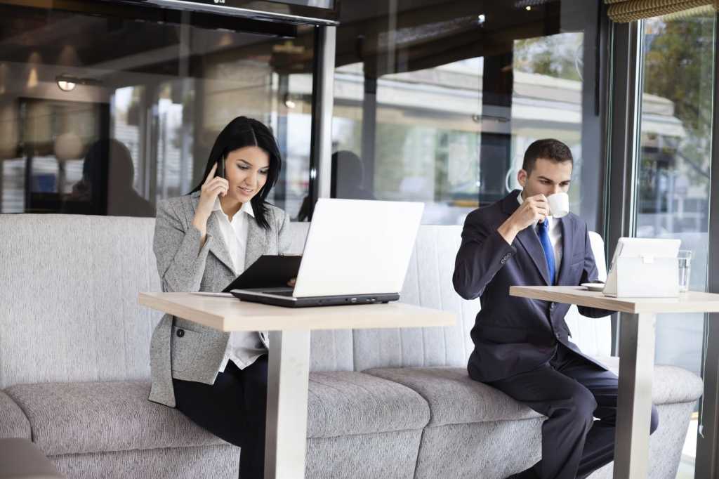 Male and female business people in coffee shop on wifi with laptops and coffee