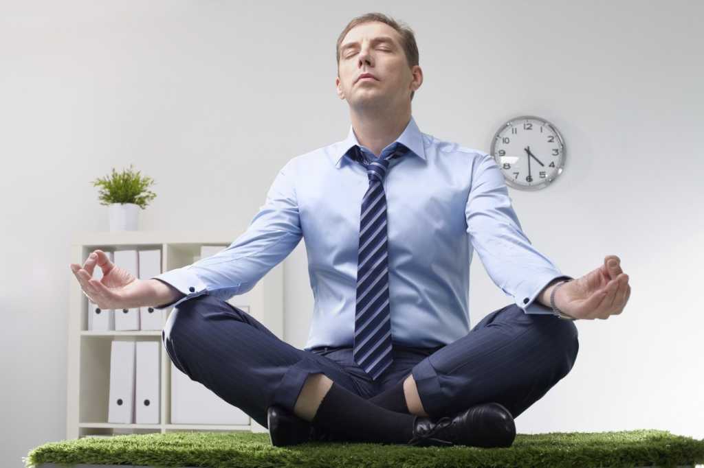 man sitting on desk doing yoga and meditating