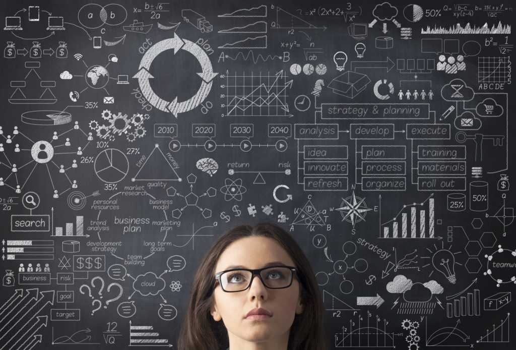 young woman in glasses standing in front of chalkboard with lots of data