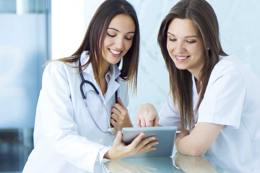 Young female doctor interacting with tablet medical records and patient