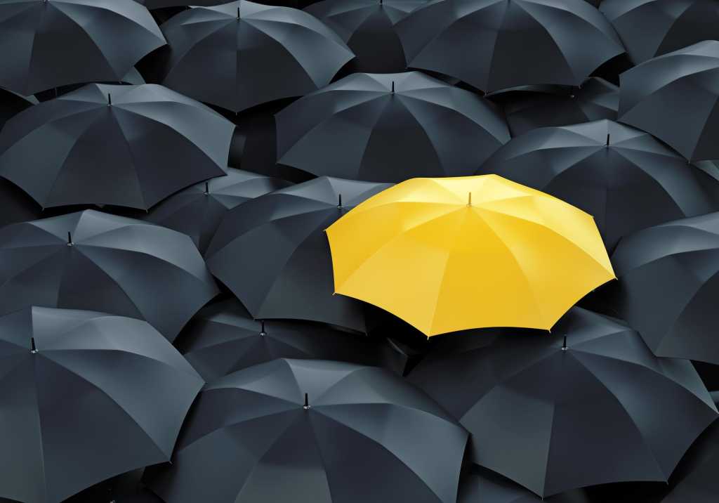 Yellow umbrella among many black umbrellas