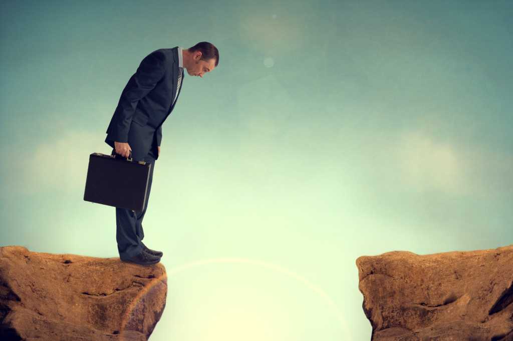 executive looking over cliff with large gap
