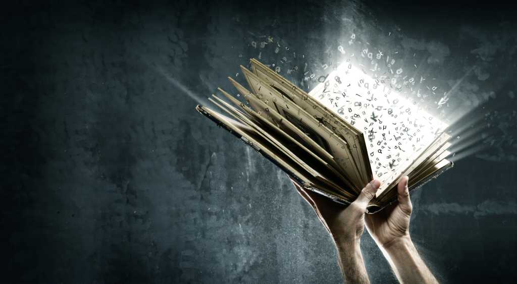 Hands holding book with exploding words