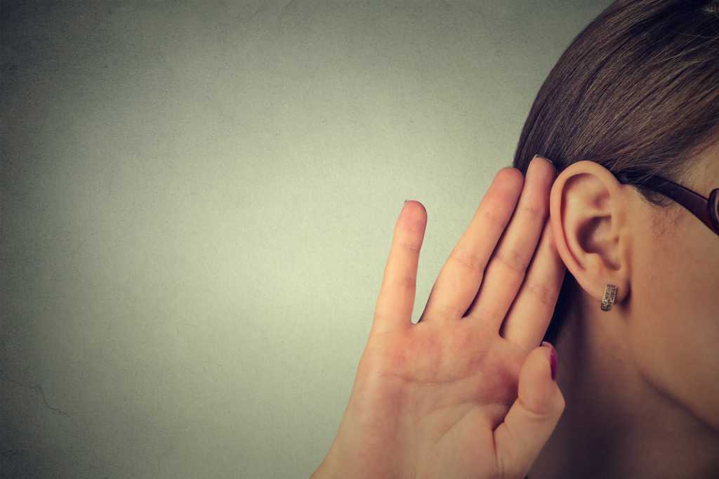 closeup of woman with hand at ear listening