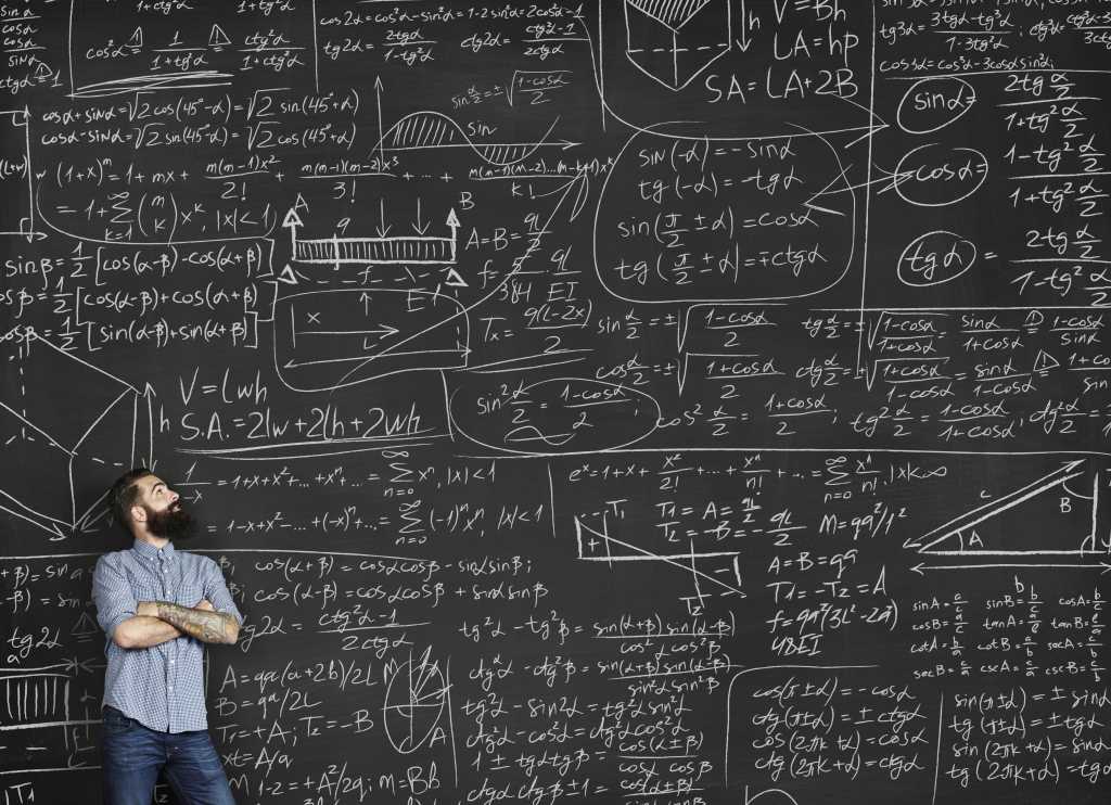 hipster millennial standing against large black chalkboard with lots of equations