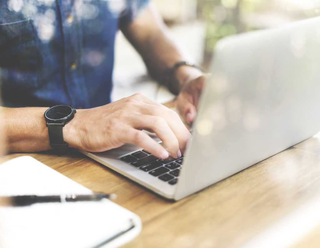 man seated at table typing on laptop