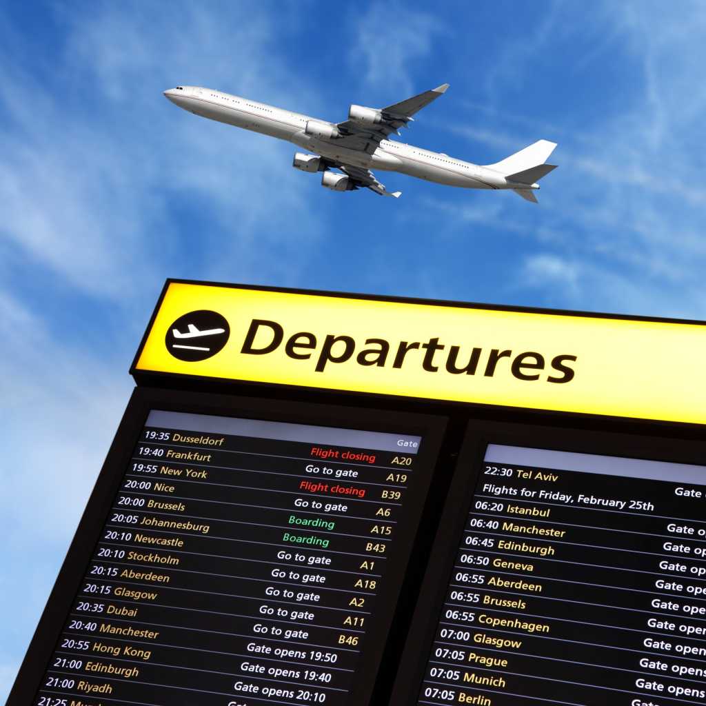 Airport departure sign with airplane flying over