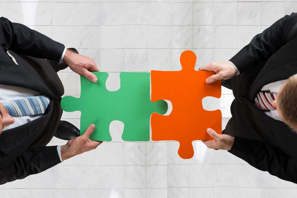 two executives holding oversized puzzle pieces