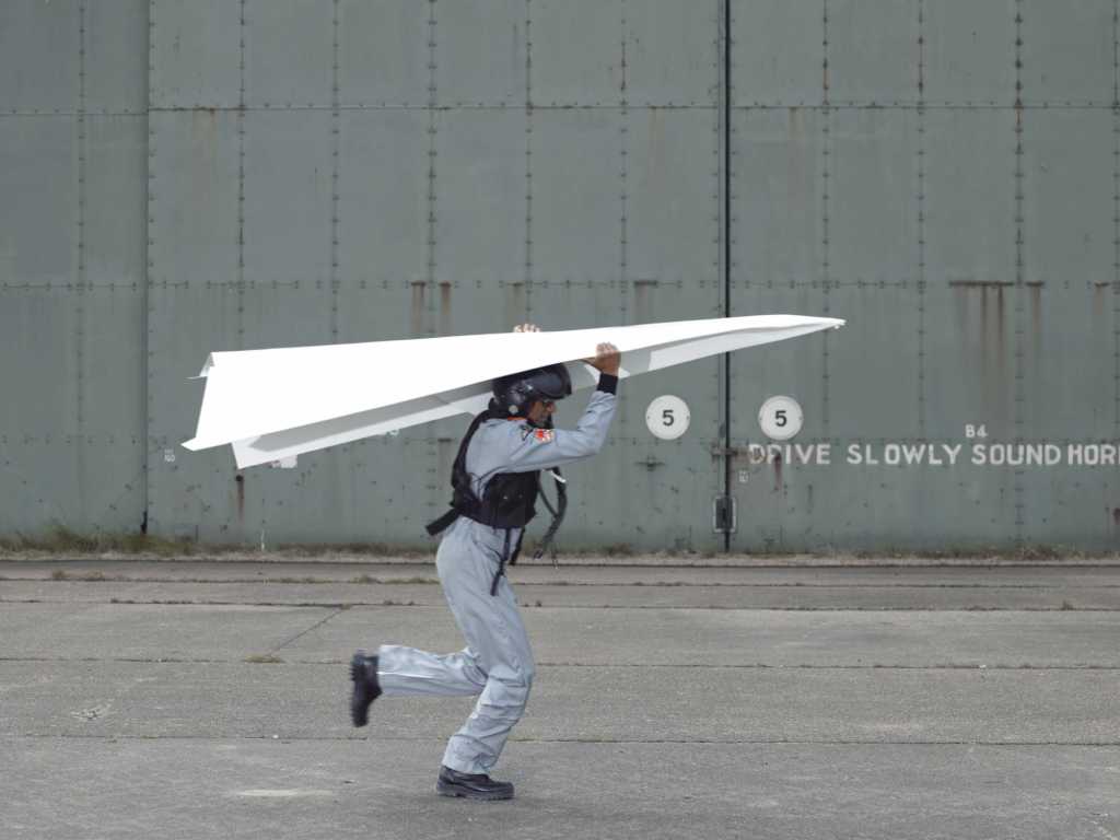 geek attempting to fly with giant paper airplane