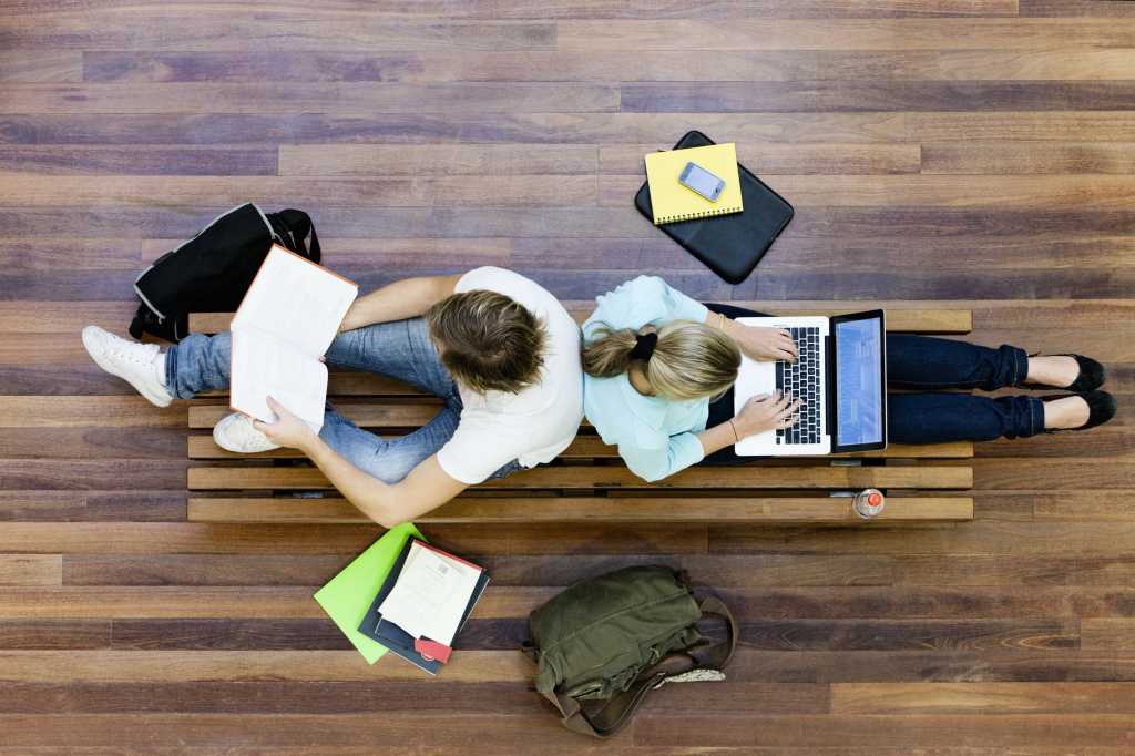Two college students from above using mobile devices on internet