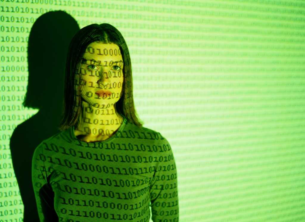 young woman in green with binary code projected on top of her