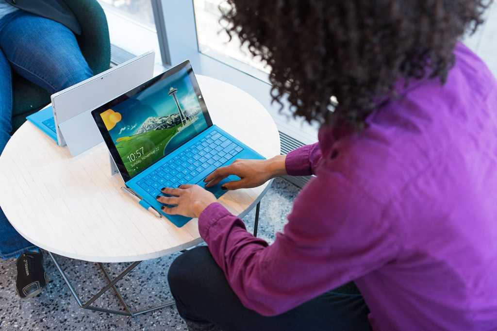 A woman using Windows on a Microsoft Surface tablet in a common area / remote worker / digital nomad