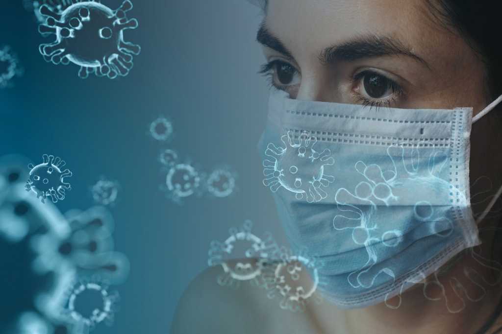 A woman wearing a face mask amid COVID-19 coronavirus morphology overlay.