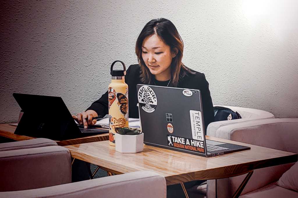 A worman in a casual workspace with Microsoft Windows laptops.