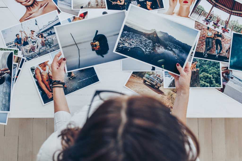 Top view of a woman photographer working in studio. Female photographer checking image prints.