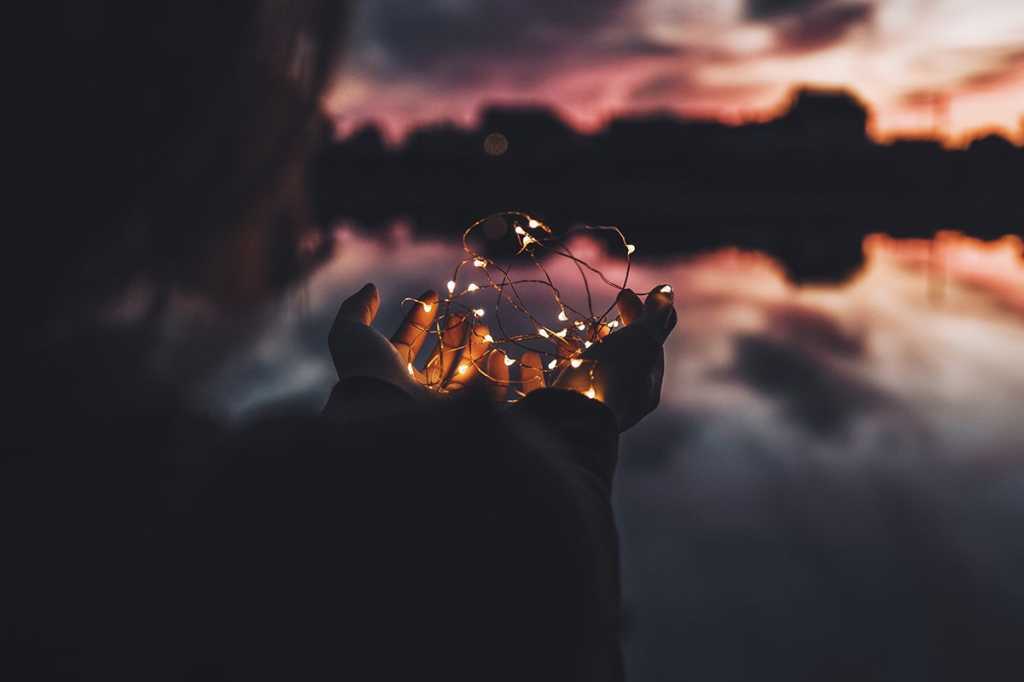 hands hold a tiny string of lightbulbs / small or emerging ideas / brainstorming / innov