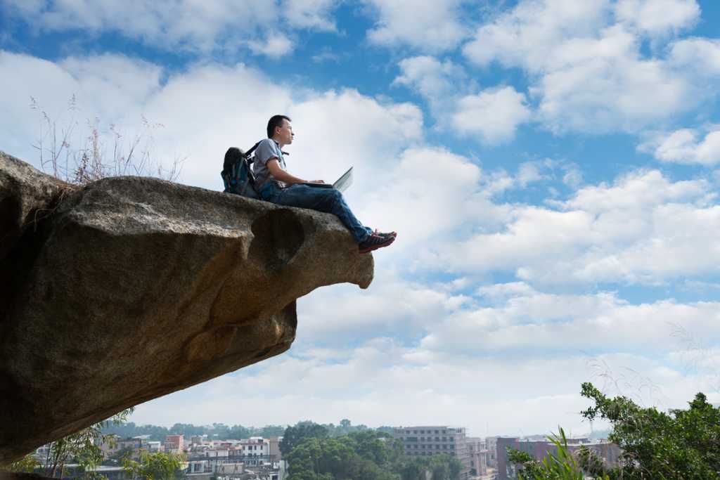 man sitting on edge of cliff