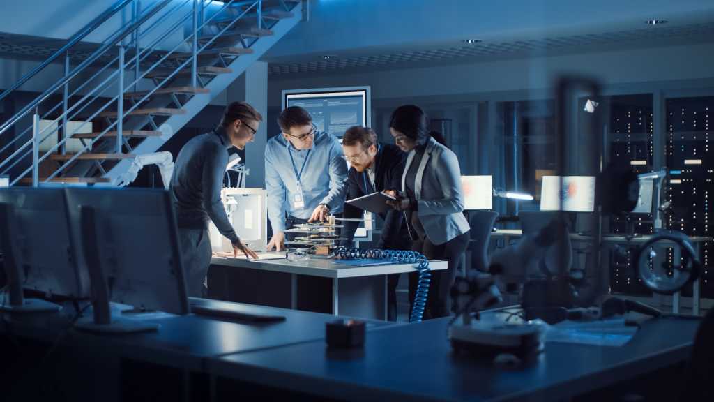 Team of Electronics Development Engineers Standing at the Desk with 3D Printer and PCB Motherboards. Specialists Working on Ultra Modern Industrial Design, Using Advanced Technology. Slow Motion