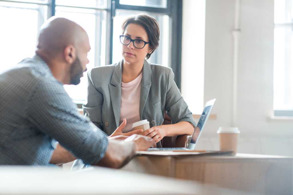 Serious woman listening to co-worker explaining new online business trends