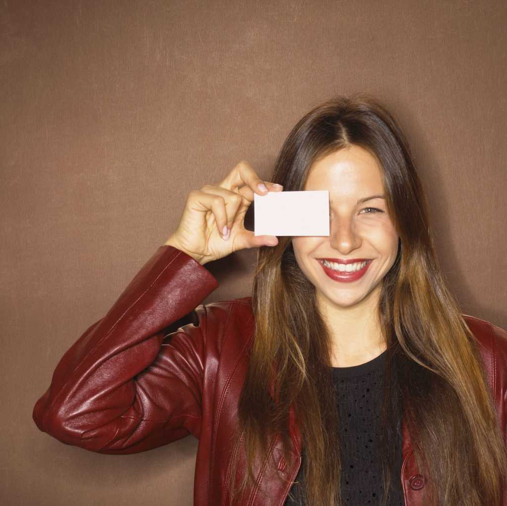 Young woman holding up business card to face